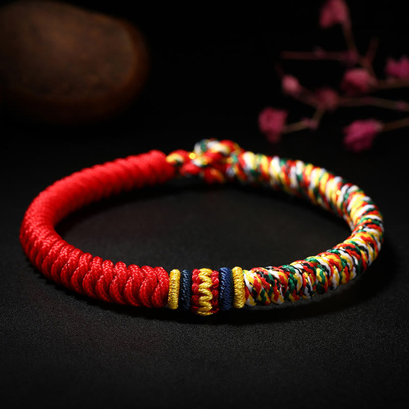 Tibetan five-color king kong knot braid bracelet with red cord and rainbow multicolor woven section featuring gold and navy blue accent bands on black background
