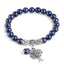 Tree of Life lapis lazuli bracelet with deep blue beads and golden pyrite flecks, silver tree-of-life charm, silver floral spacers, lapis dangle.