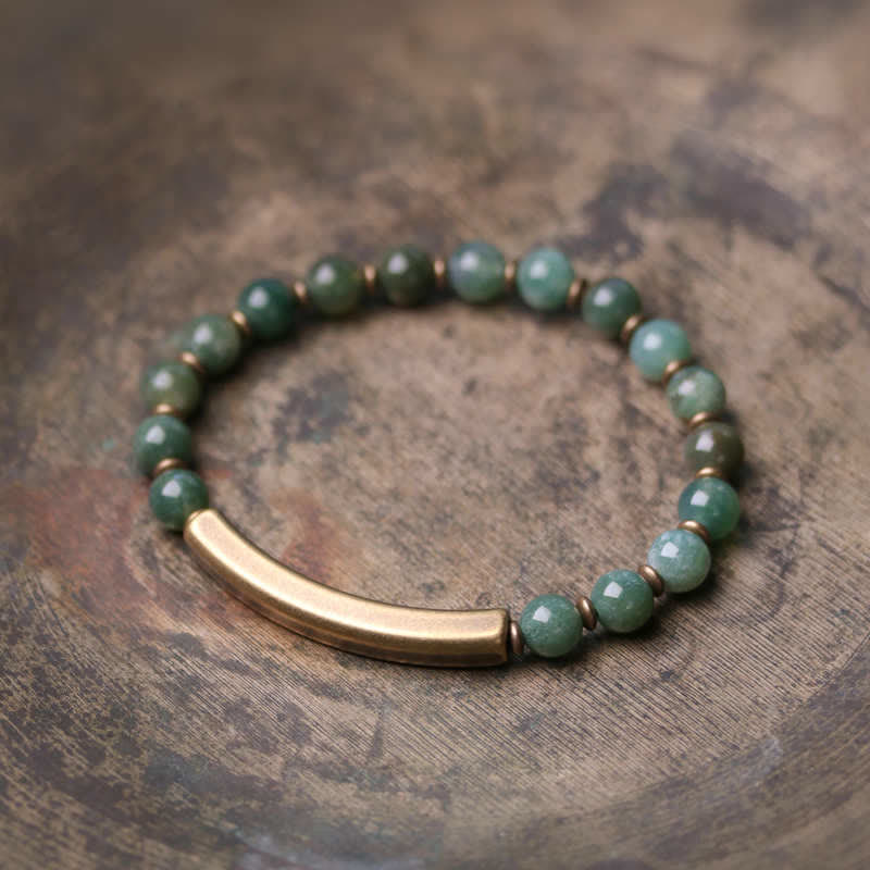 Moss agate green bracelet with antique brass curved bar on weathered wood, mottled green aventurine jade beads with natural inclusions and bronze spacers