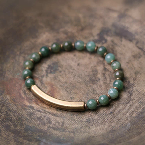 Moss agate green bracelet with antique brass curved bar on weathered wood, mottled green aventurine jade beads with natural inclusions and bronze spacers