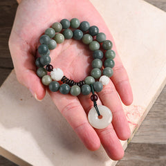 Cyan Bodhi Seed Jade Peace Buckle Bracelet - green mala beads in hand on antique book, spiritual styling