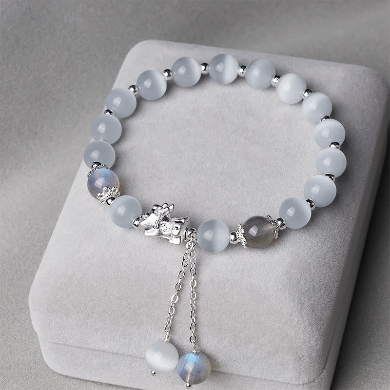 Cat's Eye PiXiu Bracelet – White cat's eye beads with silver PiXiu and moonstone tassels on gray cushion