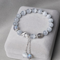 Cat's Eye PiXiu Bracelet – White cat's eye beads with silver PiXiu and moonstone tassels on gray cushion