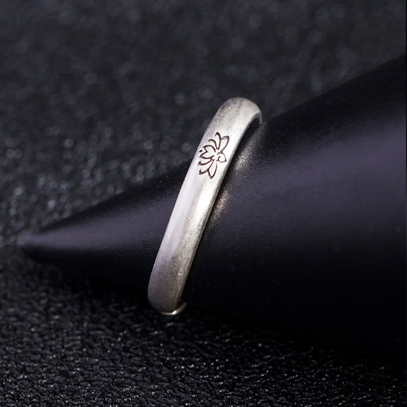 Lotus Enlightenment Ring - engraved silver floral band on dark surface with mandrel prop