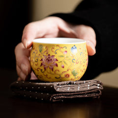 Lotus Pod Ceramic Tea Cup – cradled on tea cloth showing yellow lotus design, gongfu tea