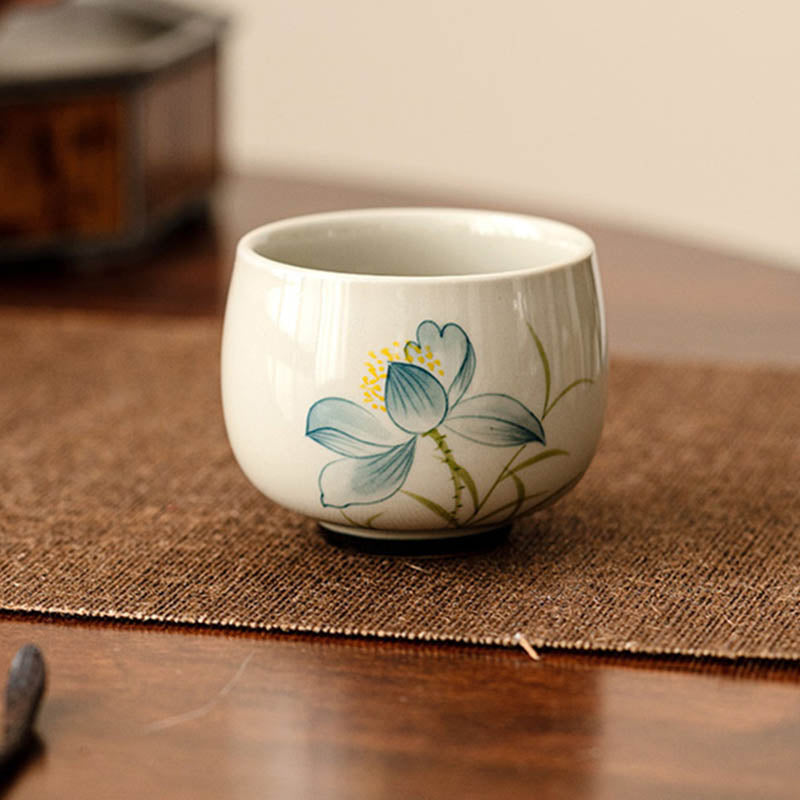 Hand Painted Lotus Tea Cup – on woven jute mat with dark wood table, blue lotus, crackle glaze, rustic zen