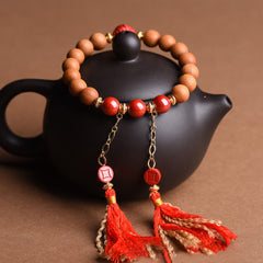 Peach Wood PiXiu Wealth Bracelet – Red cinnabar and wood bracelet draped on black teapot, wealth amulet