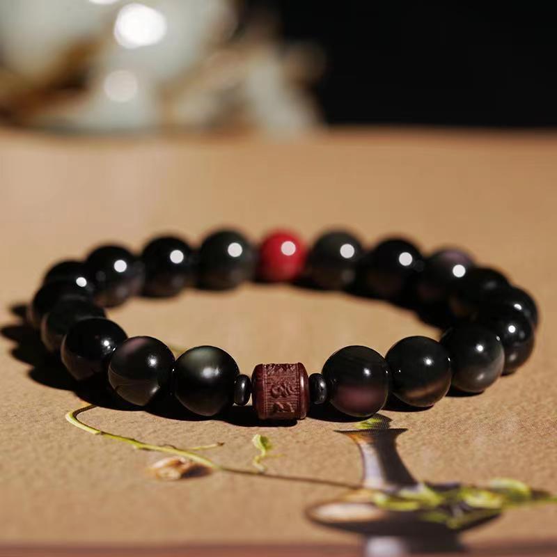 Gold Sheen & Rainbow Obsidian Fu Bracelet – on warm surface with green sprig, gemstone bracelet