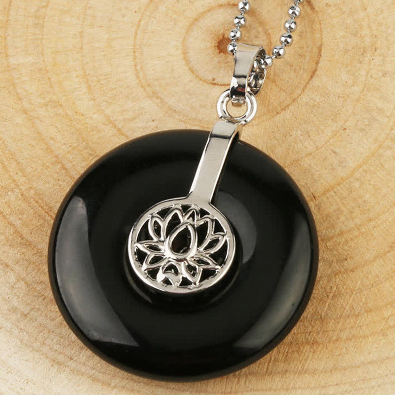 Crystal Amethyst Pink Crystal Lotus Necklace – Black obsidian lotus donut pendant with ball chain on wood, protection grounding stone
