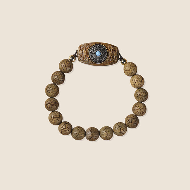 Green Sandalwood & Ebony Soothing Bracelet – centered overhead on cream background, carved floral beads with dark metal ma...