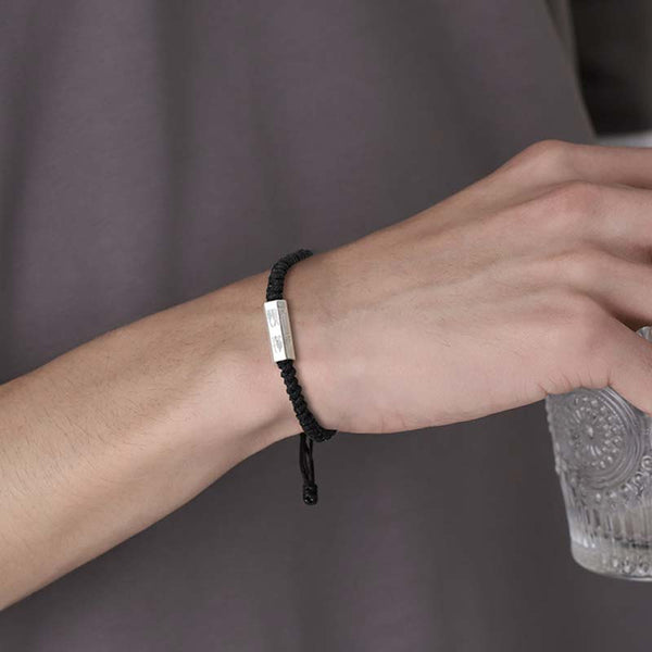 925 Sterling Silver Letter Blessing String Bracelet – Black cord with silver engraved bar worn on male wrist holding glass in lifestyle scene