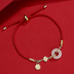 Adjustable red braided cord bracelet with white jade bi disc pendant, gold ruyi cloud charm with crystal accent and fortune blessing pendant on red background