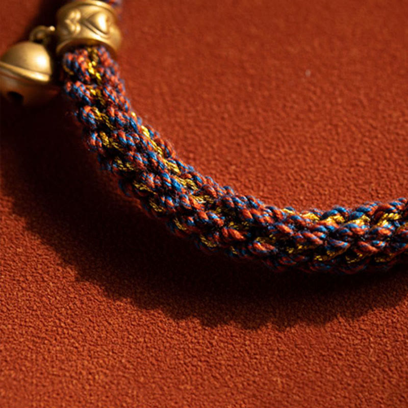 Om Mani Padme Hum Braided Bracelet – Close-up of gold bell charm and blue-gold-orange woven cord texture, handmade