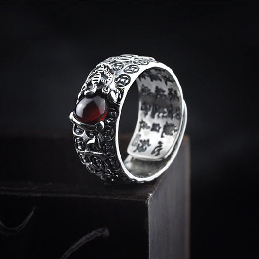 PiXiu Red Garnet Wealth Ring – On dark wood block with red garnet stone and PiXiu carving, silver adjustable ring