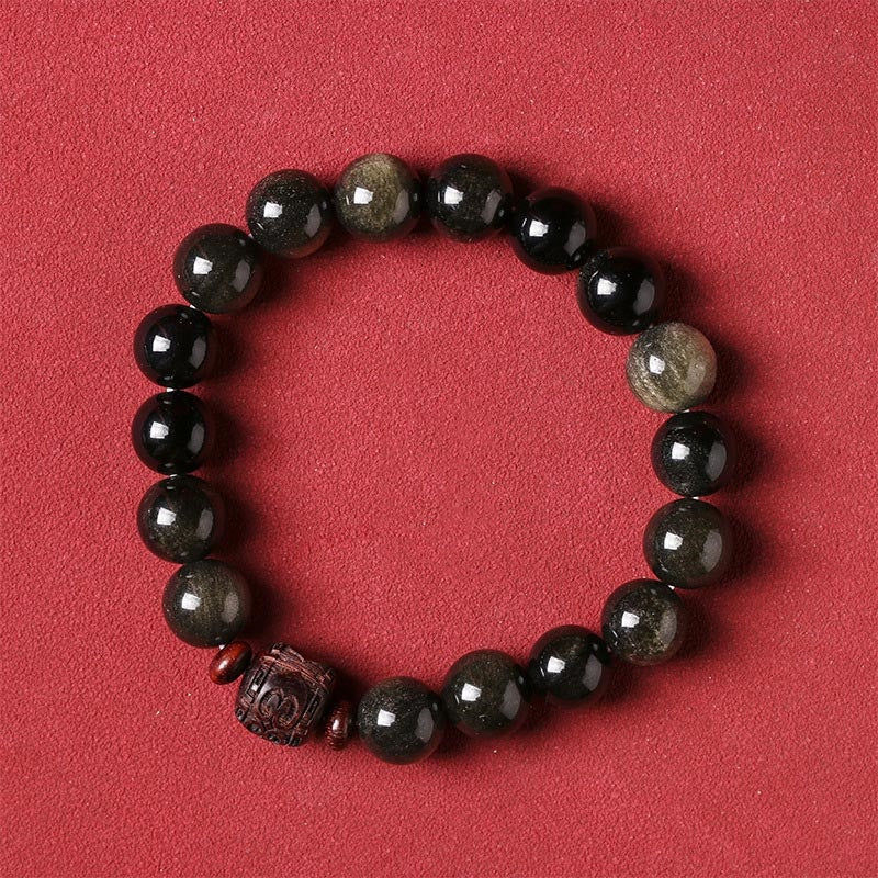 Gold Sheen & Rainbow Obsidian Fu Bracelet – on beige surface with floral branch, artisan bracelet