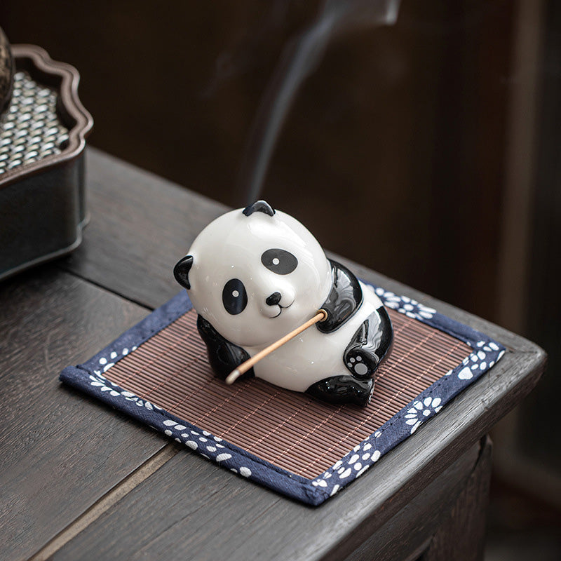 Ceramic panda incense holder with black and white glaze, smoke on bamboo mat