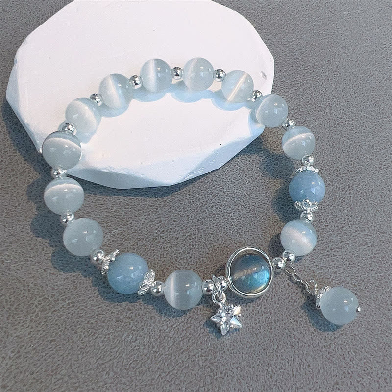 Cat's Eye Moonstone Butterfly Bracelet – Translucent white and pale blue beads with iridescent cabochon and star charm on white stone slab gray surface