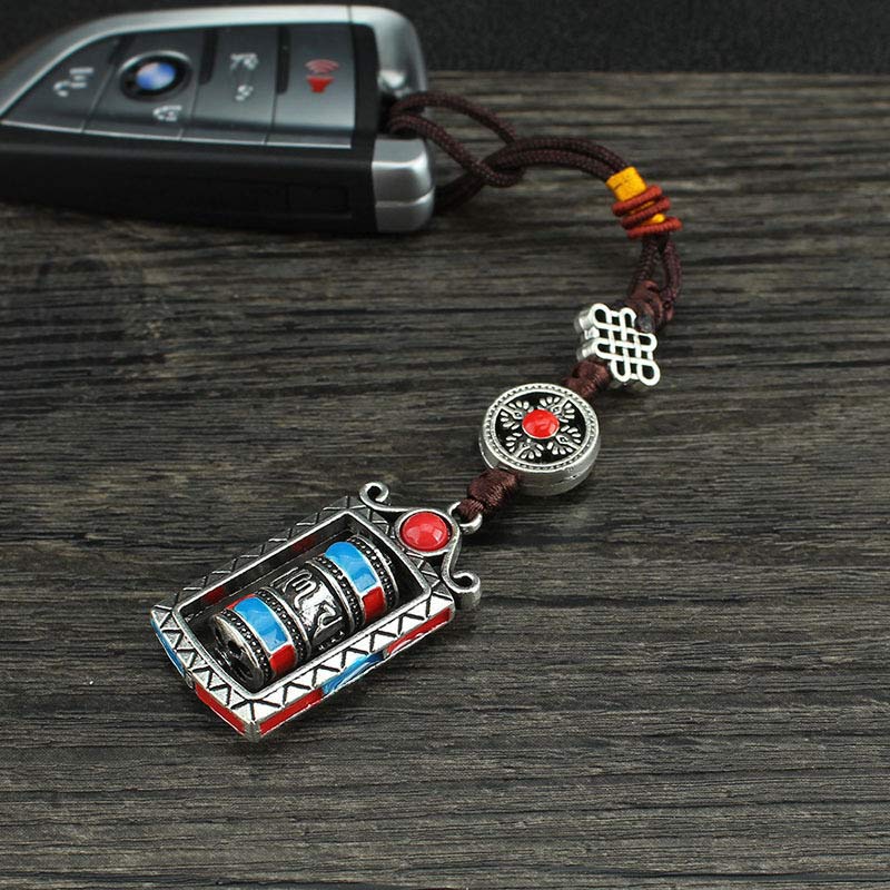 Om Mani Padme Hum Prayer Wheel Keychain – Attached to BMW car key fob on dark wood, practical keychain use