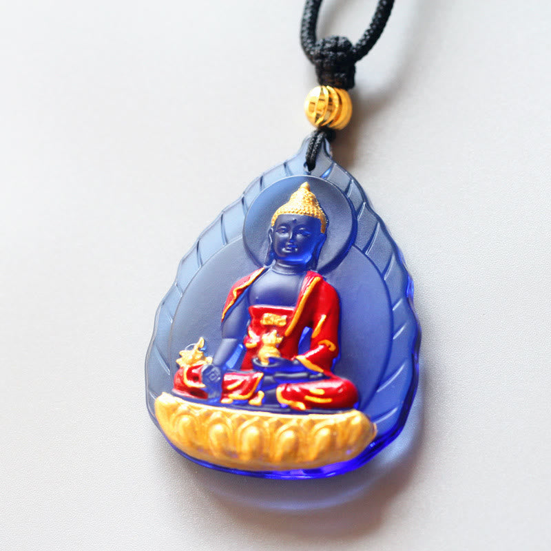 Liuli Crystal Medicine Buddha Pendant – blue liuli with gold lotus base and black cord on white, front view