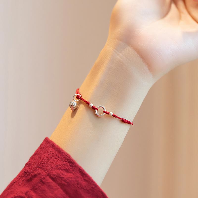 Sterling Silver Lotus Peace Buckle Red String Bracelet – Side profile of bracelet worn on wrist with sterling silver circle, spacer beads, and lotus-inspired dangle charm against warm bokeh