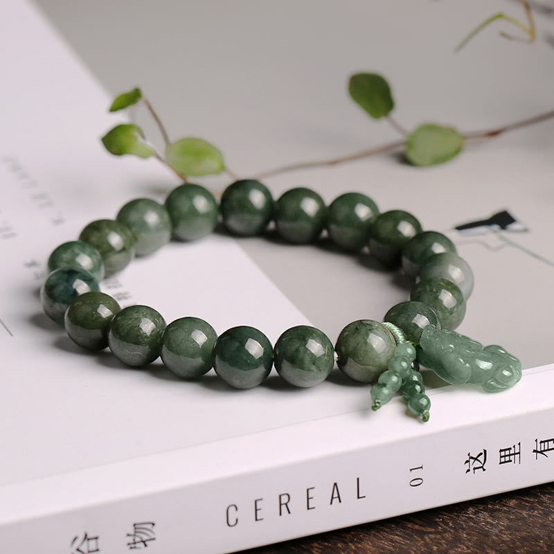 Tibetan Jade PiXiu Prosperity Bracelet – Jade PiXiu bracelet on white book with green leaves, spiritual jewelry