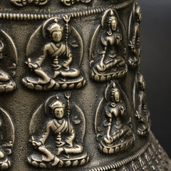 Tibetan Buddha Dragon Bell close-up seated deity relief figures on cylindrical body, trident symbols, sacred, intricate
