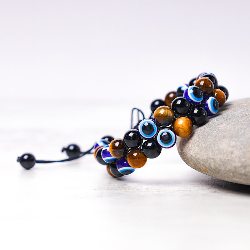 Evil Eye Tiger Eye Bracelet – side view on river stone showing adjustable cord and bead cluster