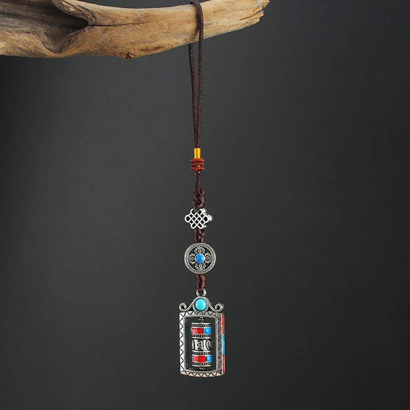 Om Mani Padme Hum Prayer Wheel Keychain – Full length hanging from wood prop, dark background, Buddhist charm