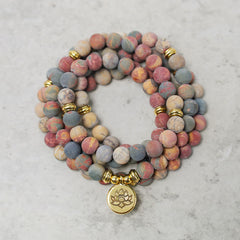 Picasso Jasper 108 Mala Bracelet - coiled flat lay with lotus charm, jasper bead bracelet