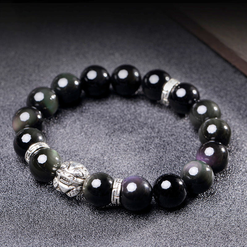 Rainbow Obsidian Bracelet – Silver PiXiu on textured gray surface, iridescent black beads, blessing