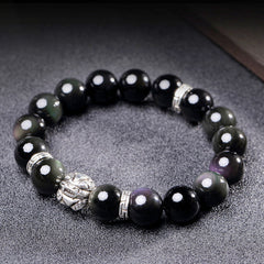 Rainbow Obsidian Bracelet – Silver PiXiu on textured gray surface, iridescent black beads, blessing