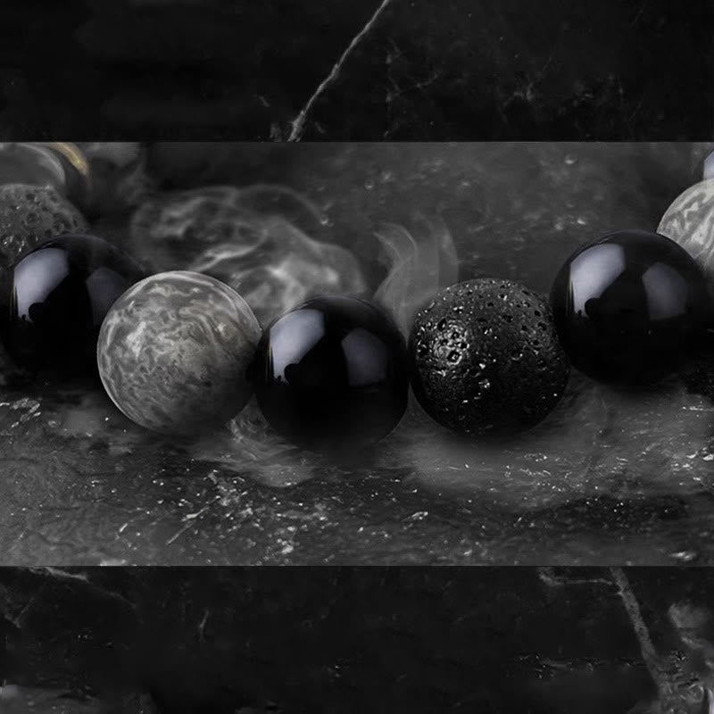 Black Obsidian Lava Rock Yin Yang Bracelet - extreme macro with smoke, glossy black beads on marble, dramatic lighting