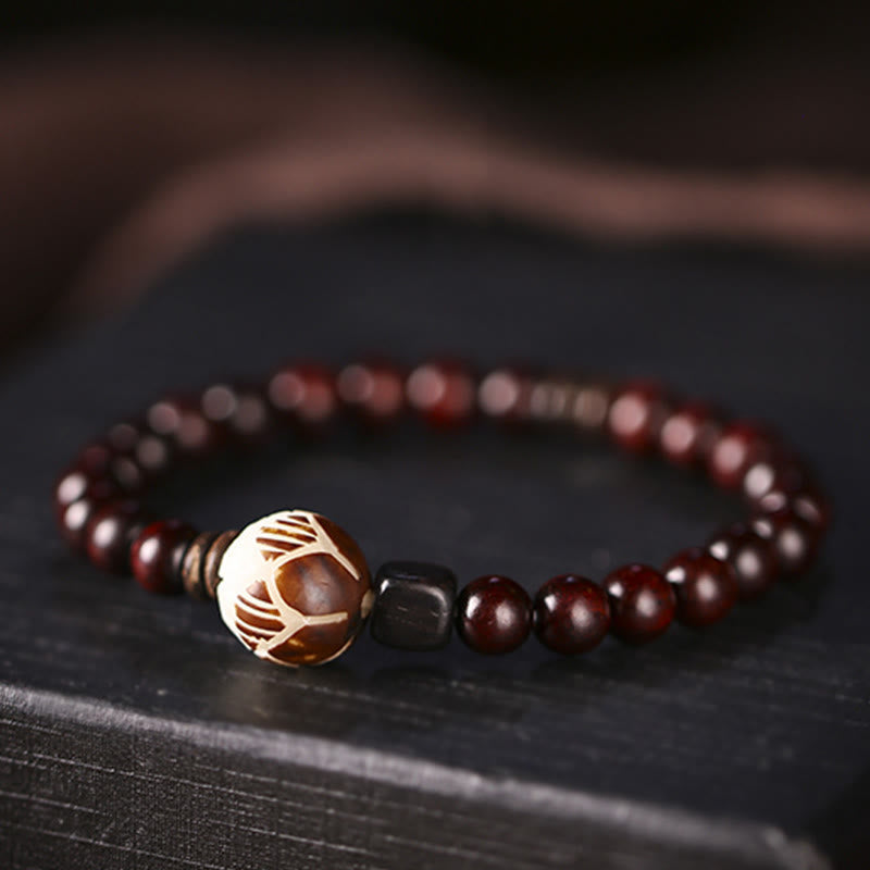 Red Sandalwood Lotus Bodhi Seed Bracelet – Carved lotus focal bead on dark burgundy wood beads, moody slate background