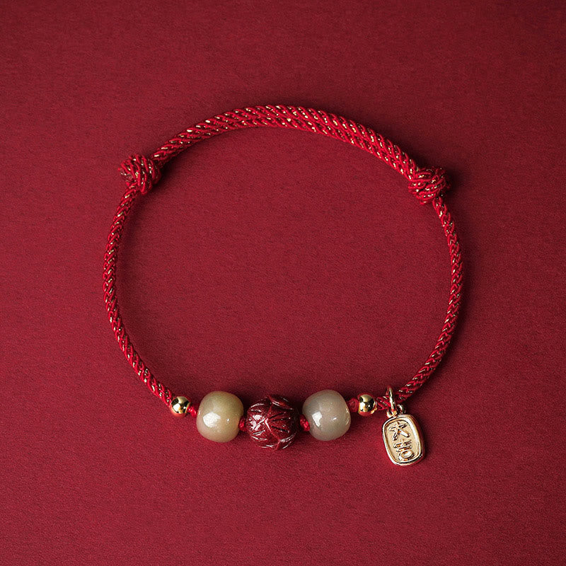 Hetian Jade Cinnabar Lotus Bracelet – Red cord flat lay with carved lotus cinnabar bead and jade stones, lucky red bracelet