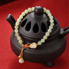 Hetian Jade Gourd Lotus Bracelet draped over black ceramic censer on crimson silk, traditional Chinese aesthetic