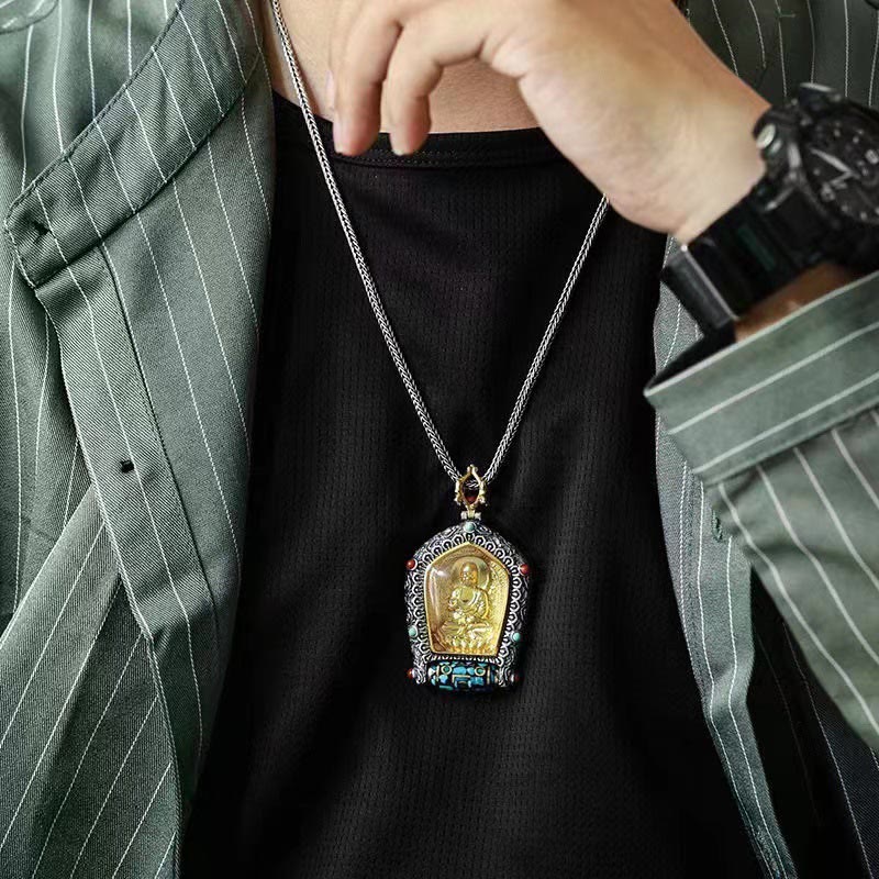 Tibetan Zodiac Buddha Dzi Bead Necklace – Gold Amitabha Buddha in silver filigree frame with turquoise coral and prayer wheel, warm brown curved wood surface close-up