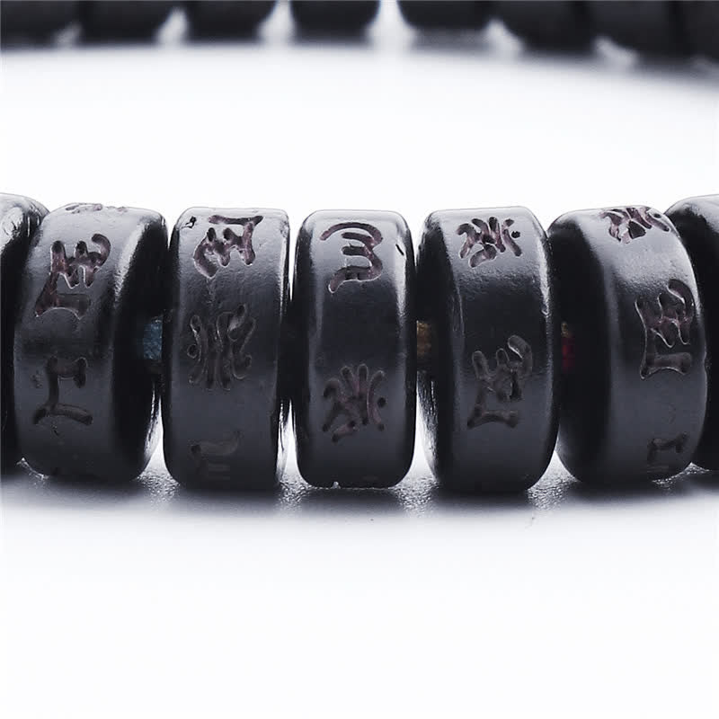 Coconut Shell Mantra Bracelet - Side profile macro of cylindrical disc beads, mantra engraving close-up