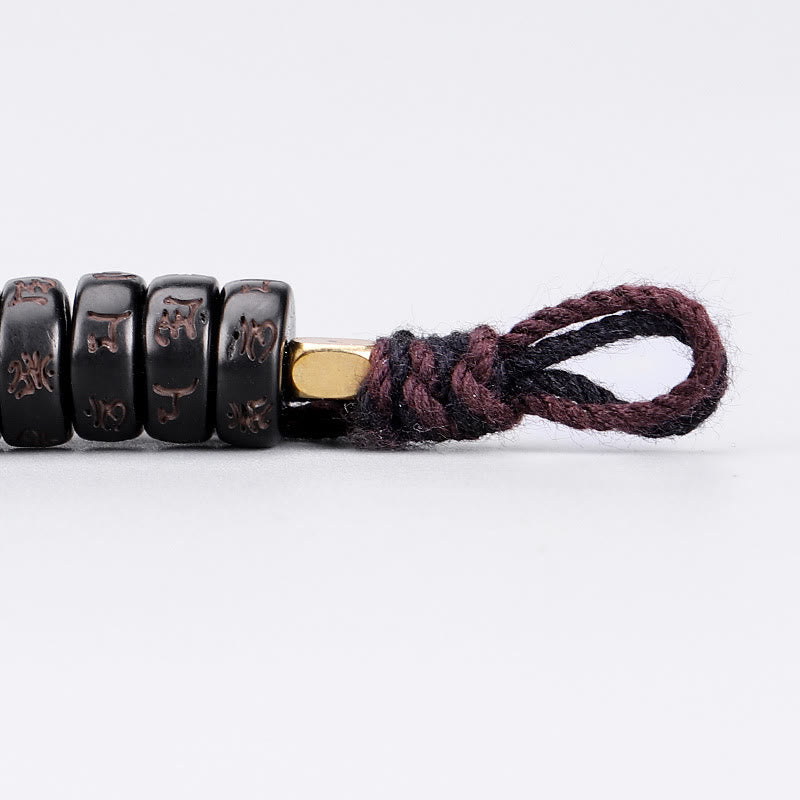 Coconut Shell Om Mani Padme Hum Bracelet – cylindrical mantra beads with gold spacer and braided burgundy cord, side profile close-up