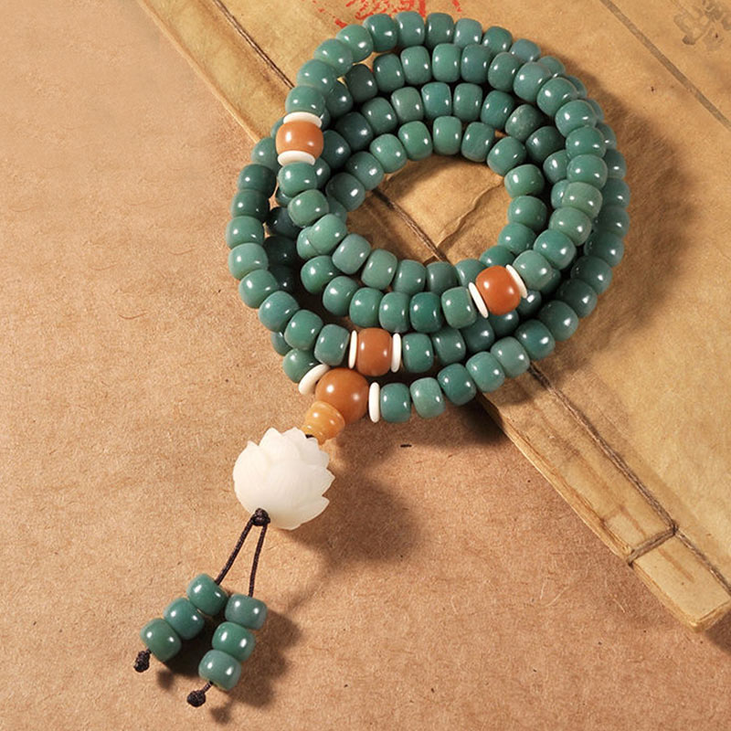 Lotus Cyan Bodhi Seed Bracelet - green barrel beads with orange markers and lotus guru bead on antique Chinese book