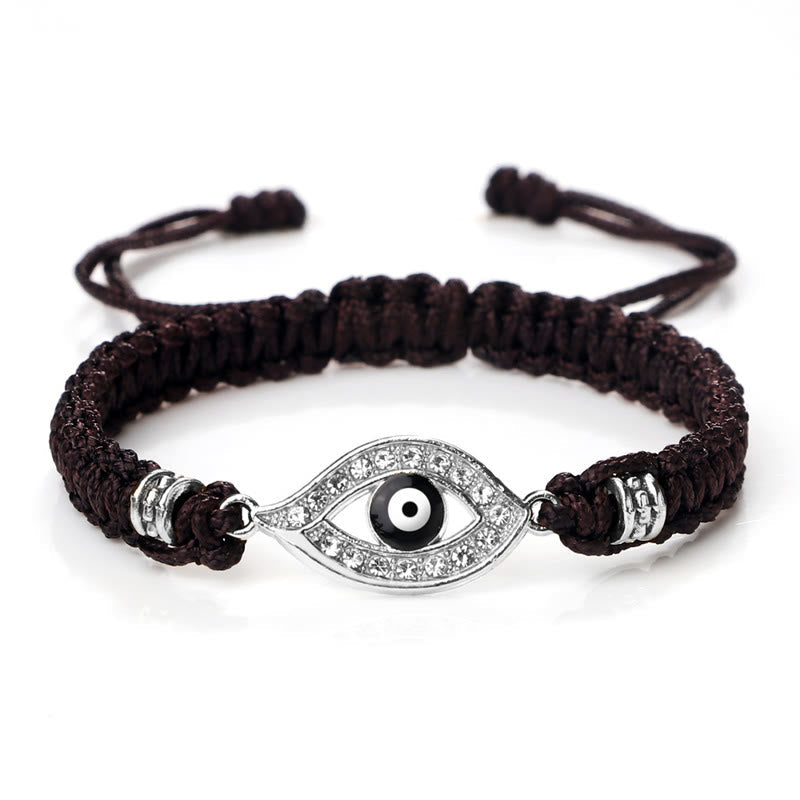 Dark brown cord evil eye bracelet with silver crystal evil eye charm on white background