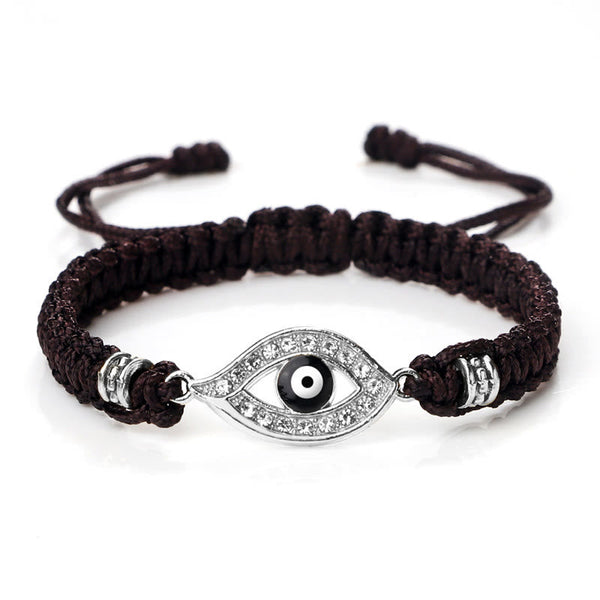 Dark brown cord evil eye bracelet with silver crystal evil eye charm on white background