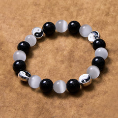 Black Obsidian Cat Eye Yin Yang Bracelet - flat lay on kraft paper showing full circular pattern, black white yin-yang bracelet