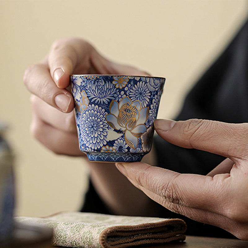 Lotus Chrysanthemum Ceramic Tea Cup - Two-hand hold revealing gold gilded chrysanthemums, intimate