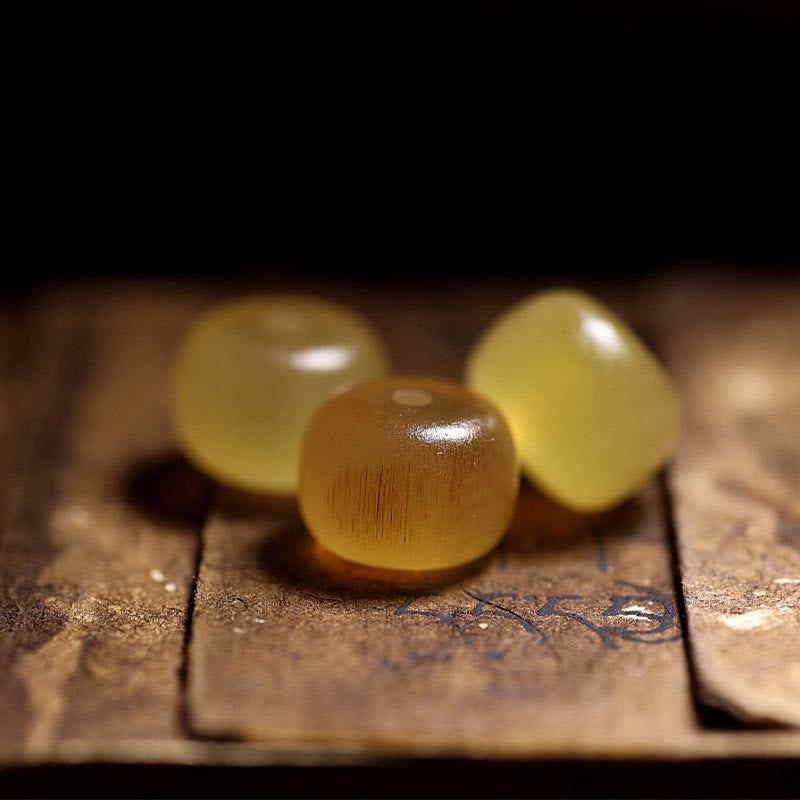 Tibetan Sheep Horn Skull Bracelet – Macro of three loose amber beads on aged manuscript, natural striations