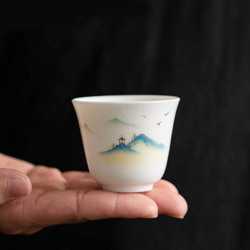 Ceramic Kung Fu Tea Cup – shanshui landscape with blue peaks and pavilion held against black backdrop, artisan craft