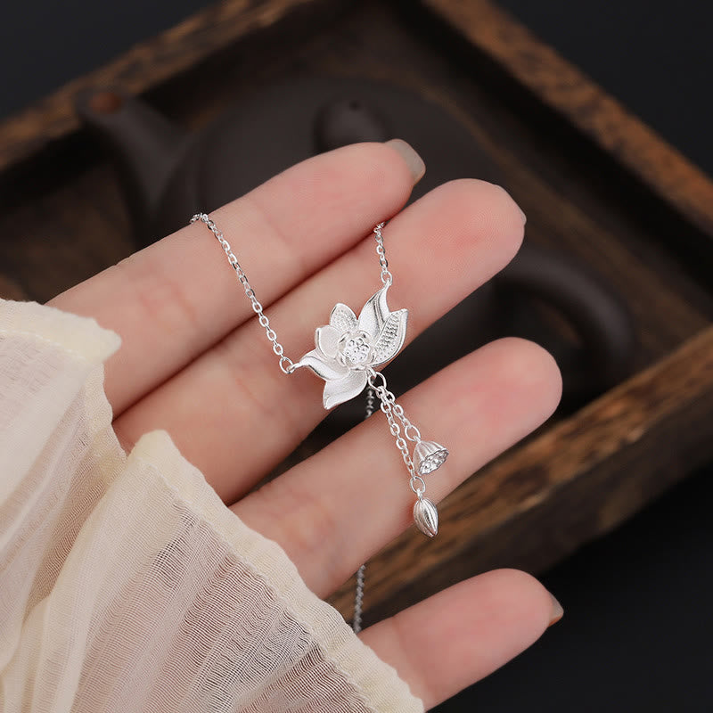 999 Silver Lotus Pod Necklace – Lotus pendant held in hand on wooden tray, ceramic teapot background, silver artisan necklace