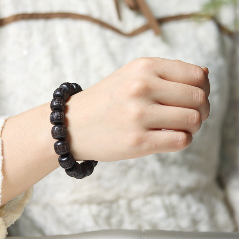 Ebony Wood Mantra Bracelet – Worn on wrist with cream knit sleeve showing natural fit, wrist jewelry