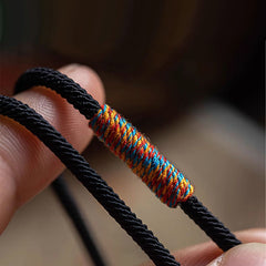 Tibetan Om Mani Padme Hum Wrap Bracelet – Worn on wrist showing double-wrap black cord, silver bead and colorful woven sections, brown background