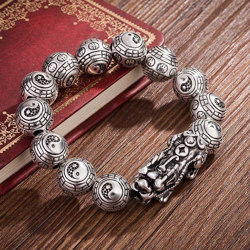 Tibetan Feng Shui PiXiu Silver Bracelet – Antique oxidized silver Pixiu charm with Tai Chi Bagua engraved beads on dark wood table with vintage red book Hauptbild