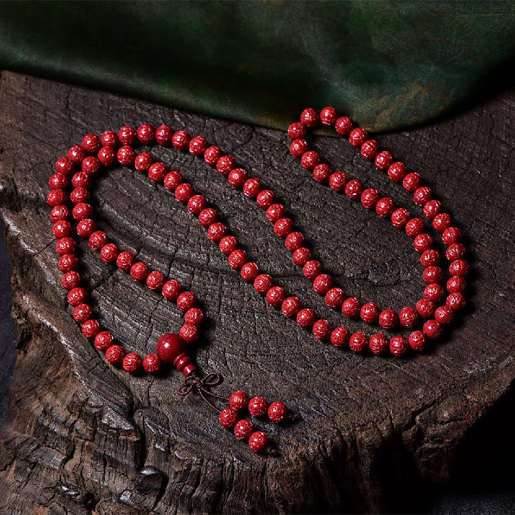108 Mala Beads Cinnabar Bracelet – Full length flat lay on wood, red carved beads